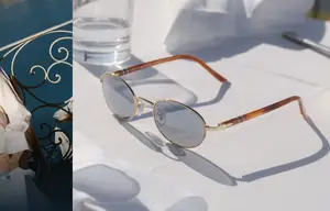 Image of sunglasses and a person wearing a white dress near a water body