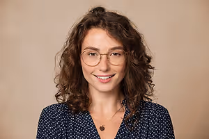 Portrait of a young woman with curly hair and glasses smiling for the camera