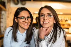 Two women with glasses smiling and posing for a photo