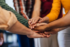 A group of people in a meeting holding hands with each other