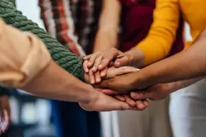 A group of people in a meeting holding hands with each other