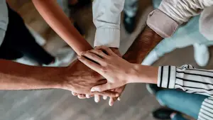 Five people with their hands stacked on top of each other