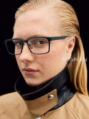 A woman with freckles wearing a black leather collar with a silver button and glasses.