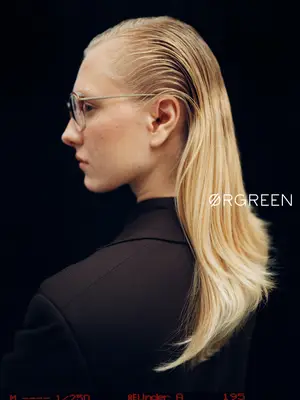 Woman with blonde hair and glasses wearing a black outfit, looking sideways.