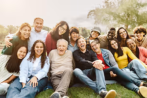 A group of people sitting on the grass and smiling for a photo