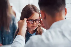 Doctor adjusting glasses of a young girl in a clinic
