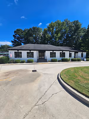 Exterior of a white optometry office with black trim, landscaped shrubs, and an American flag