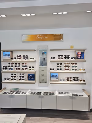 Wall display of sunglasses in an optometry practice with multiple shelves and countertop cases