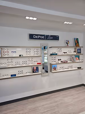 Wall-mounted optical displays showcasing eyeglass frames beneath a DePoe Luxe sign