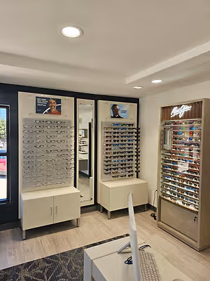 Interior of an optometry practice featuring eyeglass displays, sunglasses, mirrors, and optical cabinets