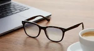 glasses on a table with a laptop and a cup of coffee