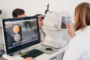 An optometrist with a young patient, using a machine to check their eye health