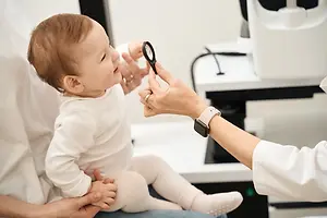 A baby is having their eyes examined by a doctor