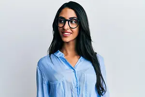 A woman with long black hair and glasses smiling for a picture