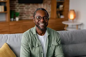African American man wearing glasses smiling for a portrait in a living room