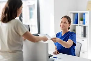 Two women in blue uniforms are having a conversation in a hospital office