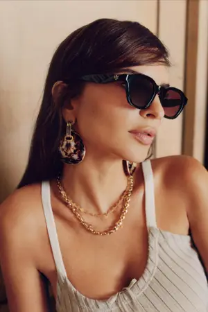 A woman is wearing sunglasses and a sleeveless top.