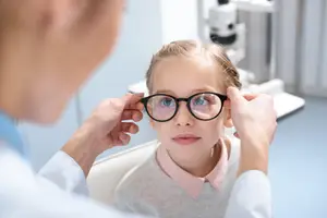 a doctor is adjusting a young girls glasses