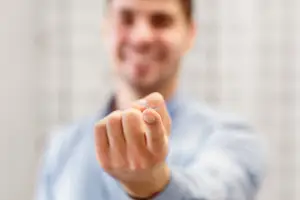 A man in a blue shirt shows off a tiny object in his hand to the camera