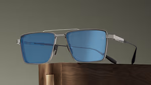 A pair of glasses with silver frames and blue lenses is placed on a wooden surface.