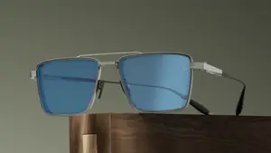 A pair of glasses with silver frames and blue lenses is placed on a wooden surface.