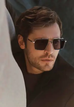 A man with sunglasses and a black coat is looking at something in front of him.