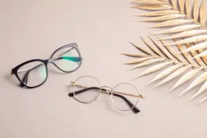 A pair of eyeglasses and golden leaves on a white surface