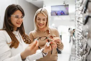 Two women looking at glasses in a store