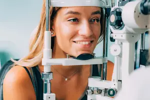 A woman is having her eyes examined by an optometrist using a medical instrument