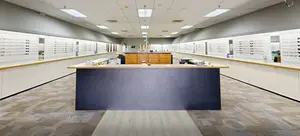 An empty room with a large counter and a row of cabinets, each with a potted plant and an array of glasses on display.