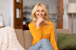 smiling middle aged woman sitting on sofa