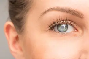 Close-up of a woman's eye with a slight squint and long eyelashes.