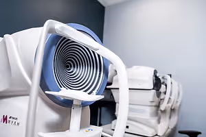 A white and blue medical machine with a spiral design in a room with a white wall and other medical machines.