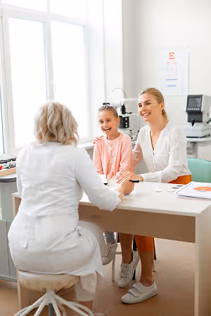 A girl smiles at the doctor during her eye exam