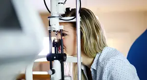A woman is looking into an eye examination machine
