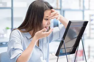 a woman looking at a mirror with a painful expression on her face
