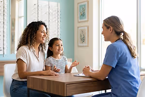 Optometrist speaking with a mother and daughter in an eyewear shop