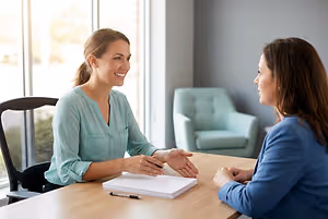 Two women discussing paperwork at a consultation table