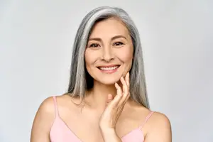 A woman with gray hair smiling and posing for a picture