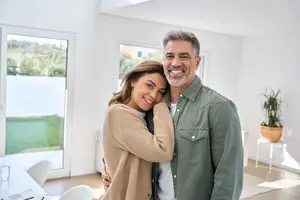 A couple smiling and hugging each other in a living room