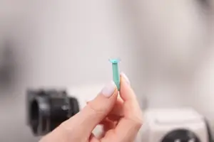 A person holding a cyan-colored glass slide with a blurry background