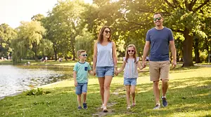 A family walks through a park in front of a lake