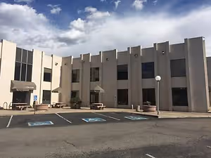 A large building with many windows and a parking lot in front of it