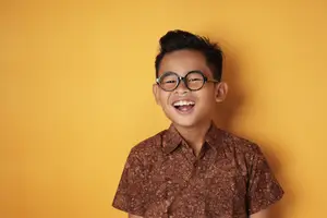 Young boy in glasses and patterned shirt smiling