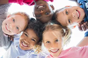 a group of children standing together with their arms around each other smiling