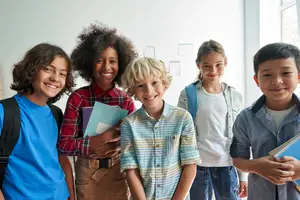 A group of school children are smiling and posing for a picture in a classroom.