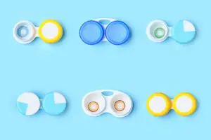Six colored contact lenses in containers against a blue background