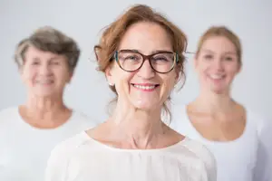 Three smiling women with short hair standing against a white background