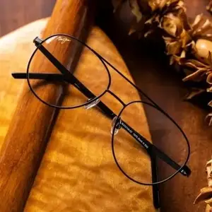 Black round glasses with thin frames on a wooden tray with decorative items