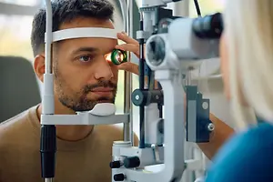 A man is having his eyes examined by a woman in a clinic.